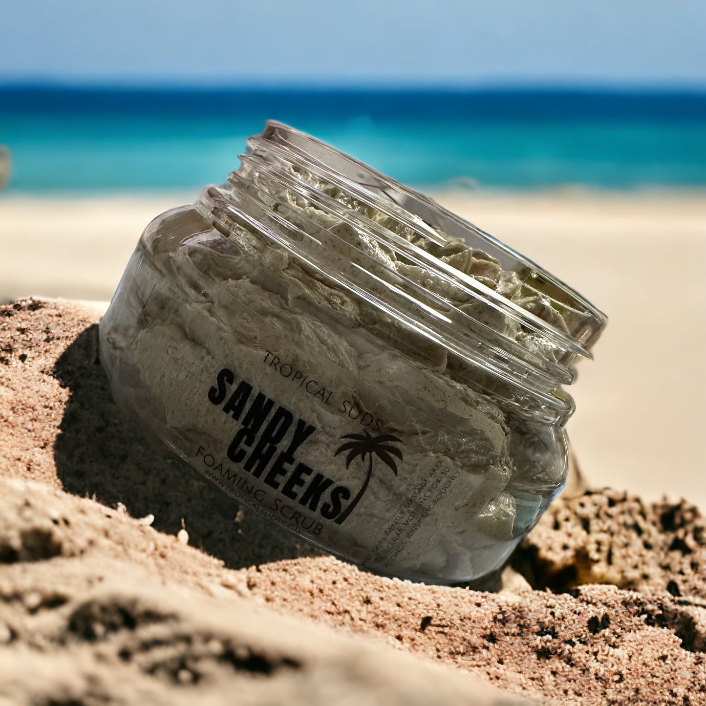 scrub in jar resting on sand by the ocean 