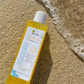yellow shower gel laying on sand by the beach