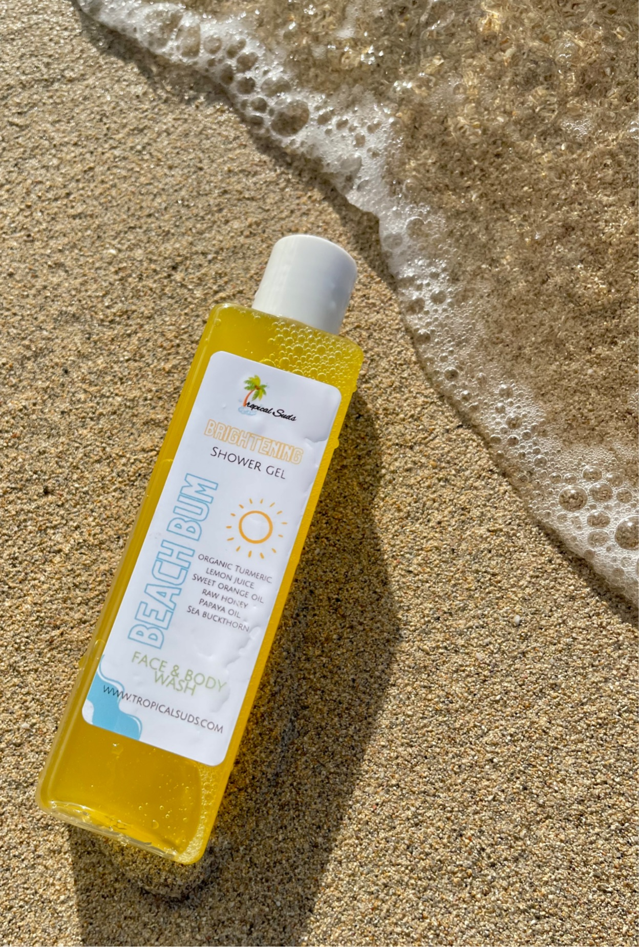 yellow shower gel laying on sand by the beach