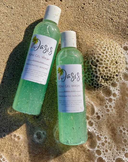 2 light blue shower gels laying on sand by the beach with bubbles 